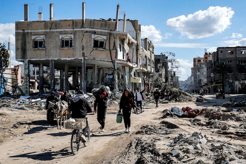 People walk past destroyed buildings destroyed by Israeli bombardment in the Maghazi camp in Gaza.