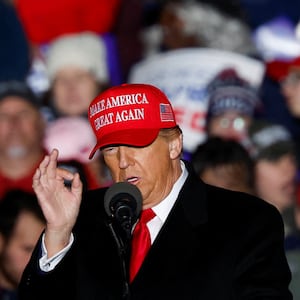 A photo of Donald Trump at a rally with a crowd behind him.