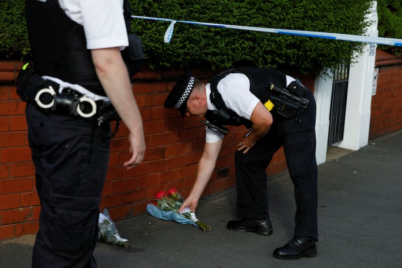 A police officer places flowers, given by residents, behind the police cordon near the scene of a stabbing incident.