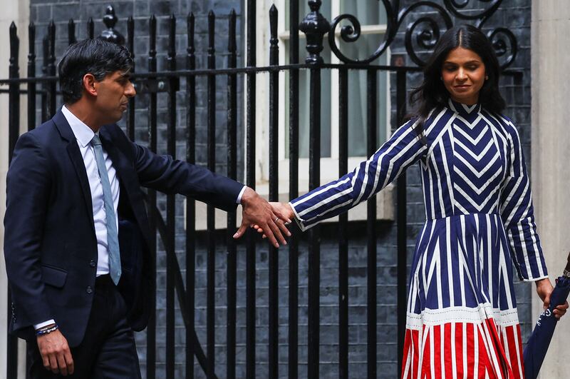 Outgoing British Prime Minister Rishi Sunak holds hands with his wife Akshata Murty, as they leave Number 10 Downing Street