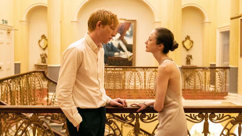 Andrea Riseborough and Domhnall Gleeson sit in a field in a still from ‘Alice & Jack’