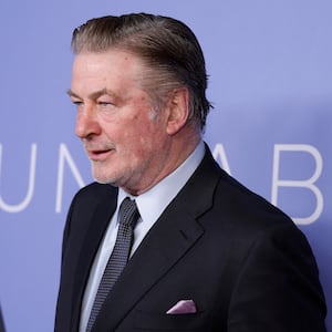 Alec Baldwin, wearing a suit and tie, stares forward at an event.