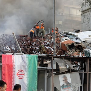 Emergency and security personnel extinguish a fire at the site of strikes which hit a building annexed to the Iranian embassy in Syria's capital Damascus, on April 1, 2024.