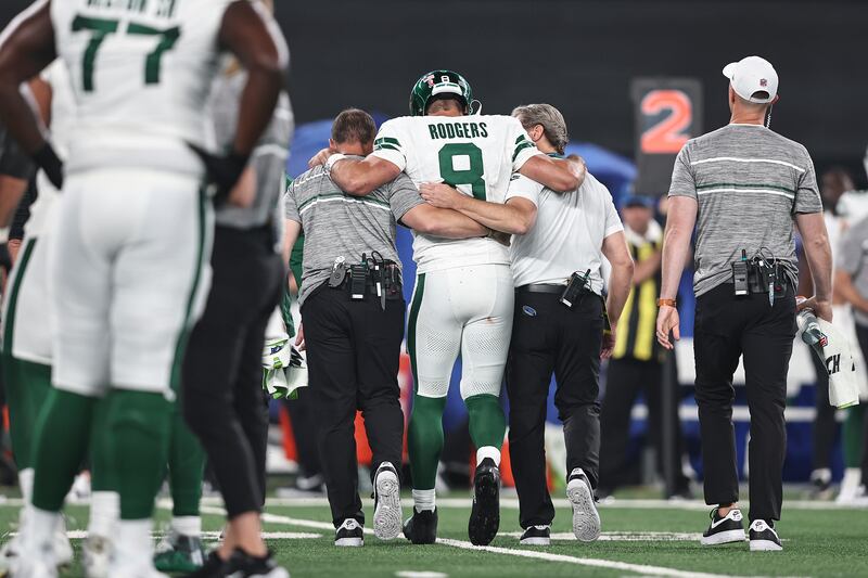 Aaron Rodgers of the New York Jets is helped off the field for an apparent injury.