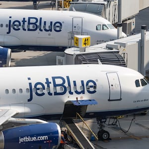 Two JetBlue planes parked at an airport.