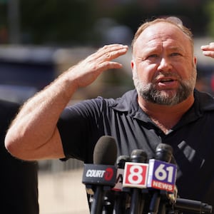 Alex Jones raises his hands while speaking at a press conference.