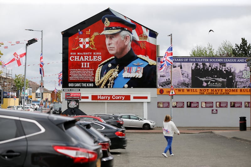 A person walks near a mural of Britain's King Charles on the side of a building, on the day of King Charles and Queen Camilla's coronation, in west Belfast, Northern Ireland May 6, 2023.