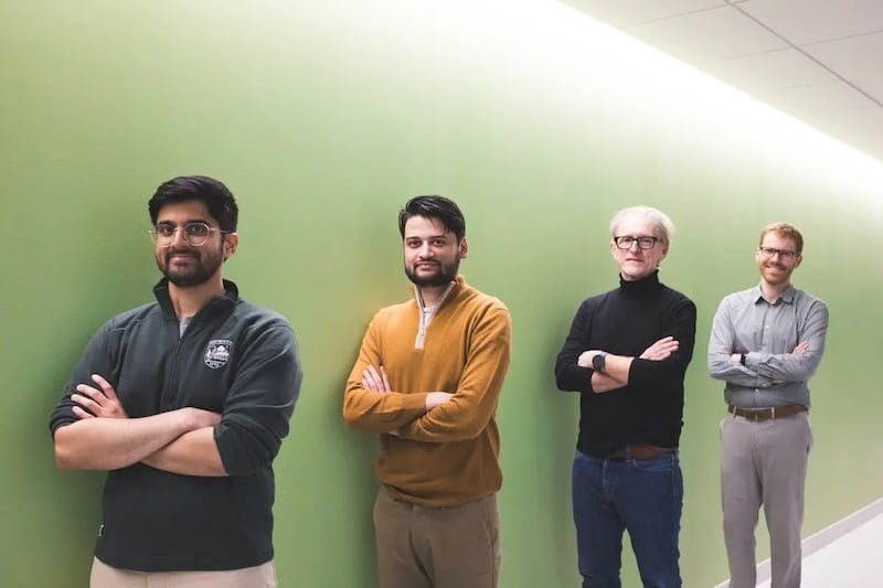 Four men stand in a line with their arms crossed. 