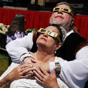 Two brides and grooms look up at the solar eclipse from an Arkansas field.