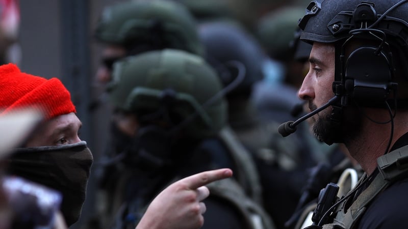 A protester over the death of George Floyd confronts a law enforcement officer dressed in riot gear