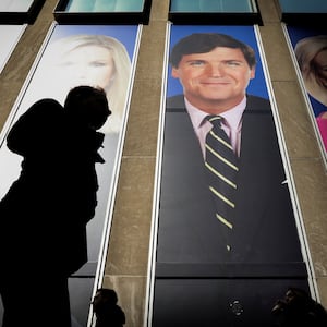 People pass by a promo of Fox News host Tucker Carlson on the News Corporation building in New York.