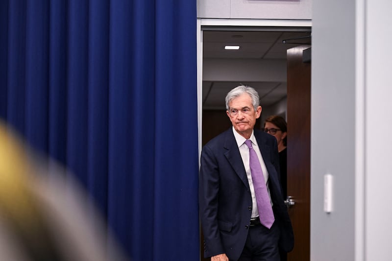 Jerome Powell walks through a door to a press conference room.