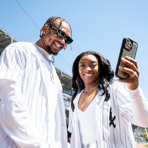 Jonathan Owens smiles alongside Simone Biles on the field at a baseball game.