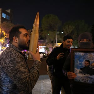 A demonstrator kisses a bullet shell replica as others gather at Palestine Square in Tehran on April 14, 2024, after Iran launched a drone and missile attack on Israel.