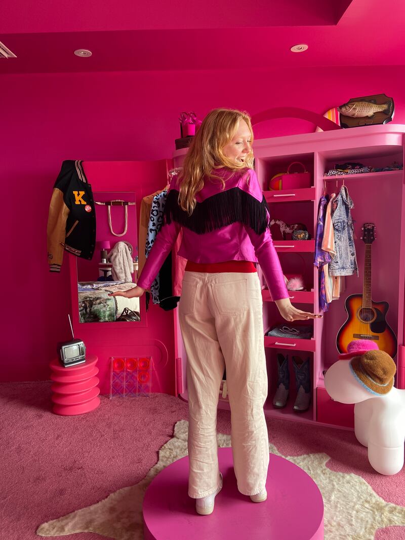 Fletcher trying on a pink Western jacket in a pink bedroom, in front of a wardrobe.