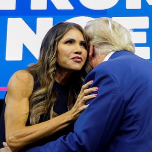 A photo of Kristi Noem embracing Donald Trump onstage at a rally.