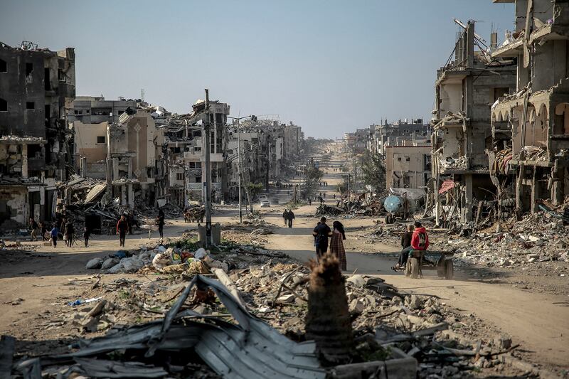 Palestinians walk past buildings destroyed during Israeli strikes in Beit Lahia in northern Gaza.