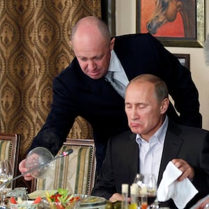 Yevgeny Prigozhin, left, assists Russian Prime Minister Vladimir Putin during a 2011 dinner 