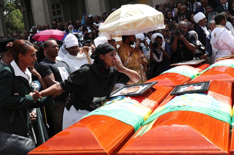 A woman mourns next to coffins during the burial ceremony of the Ethiopian Airlines Flight ET 302 crash victims