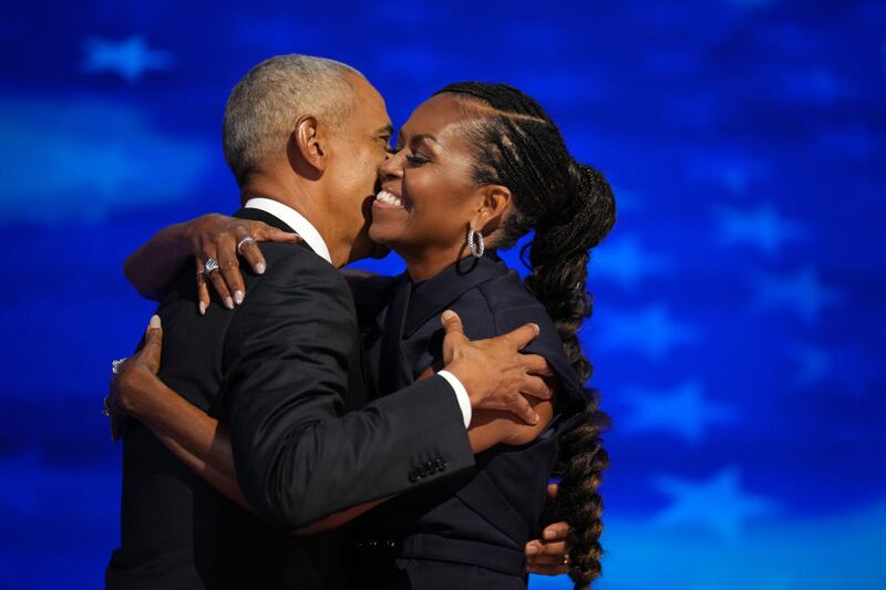 Former U.S. President Barack Obama, left, greets former first lady Michelle Obama as he arrives to speak on stage during the Democratic National Convention.