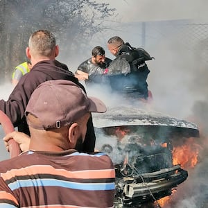 Firefighters douse a burning car after it was hit in an Israeli strike in Lebanon's southern area of Tyre.