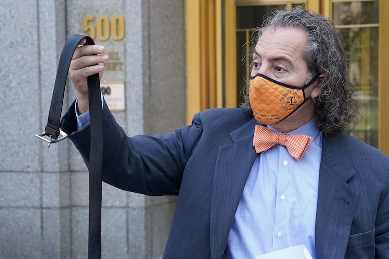 A man in a mask holds up a belt outside a court