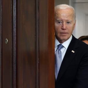 President Biden peeks out from behind a door before delivering remarks at the White House. 