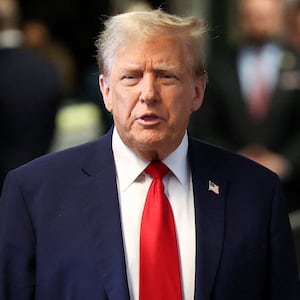 Donald Trump speaks while leaving court in a suit and tie.