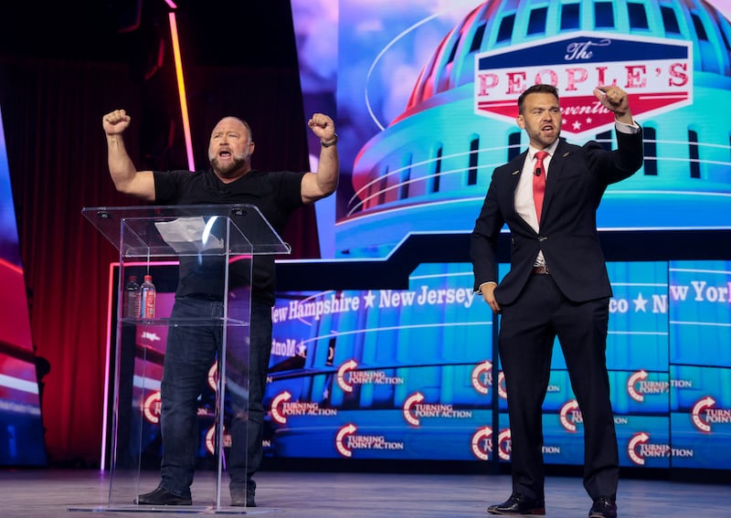 Far-right political activist Jack Posobiec and conspiracy theorist Alex Jones chant slogans at a Turning Point USA event.