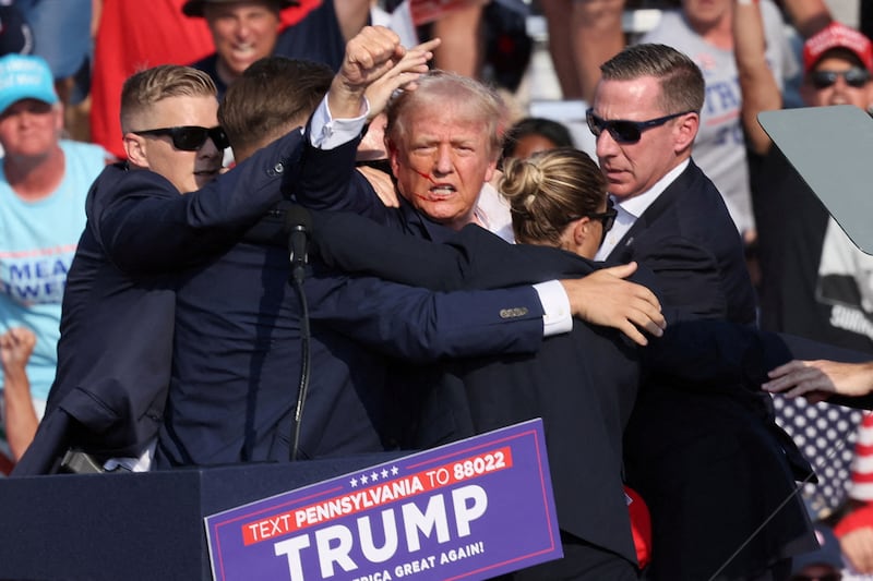 A bloodied Donald Trump raises his fist seconds after his ear was injured by a 20-year-old gunman.