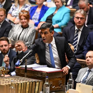 Rishi Sunak speaking at a podium with people seated behind him. 