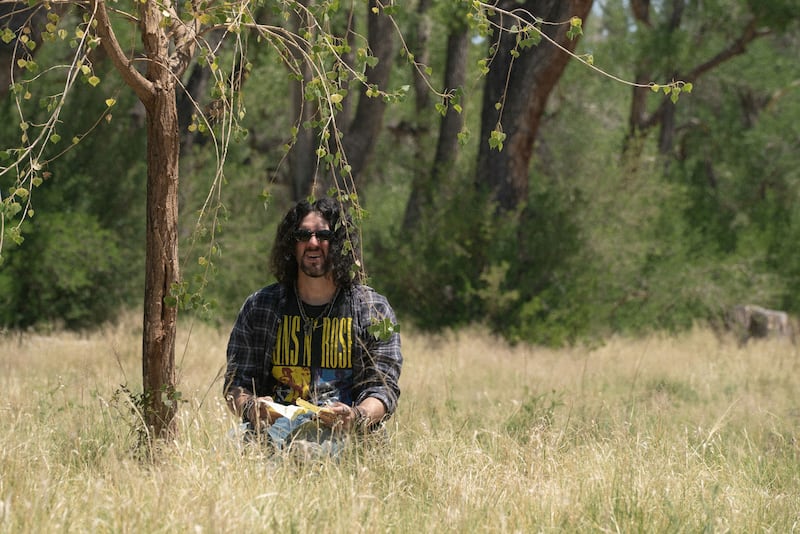 Benny Safdie stands under a stree in a still from 'The Curse'