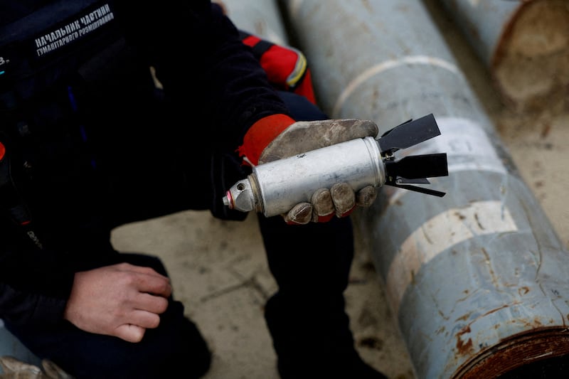 A Ukrainian soldier holds a defused Russian cluster bomb from an MSLR missile near Kharkiv, Ukraine.