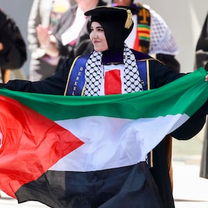 Graduate Malak Afaneh waves a Palestinian flag as she crosses the stage to receive her degree during the UC Berkeley Law School commencement at the Greek Theater in Berkeley Friday, May 10, 2024.