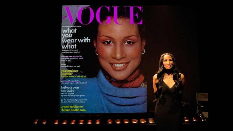 A photo of Beverly Johnson in front of a Vogue cover on which she is depicted