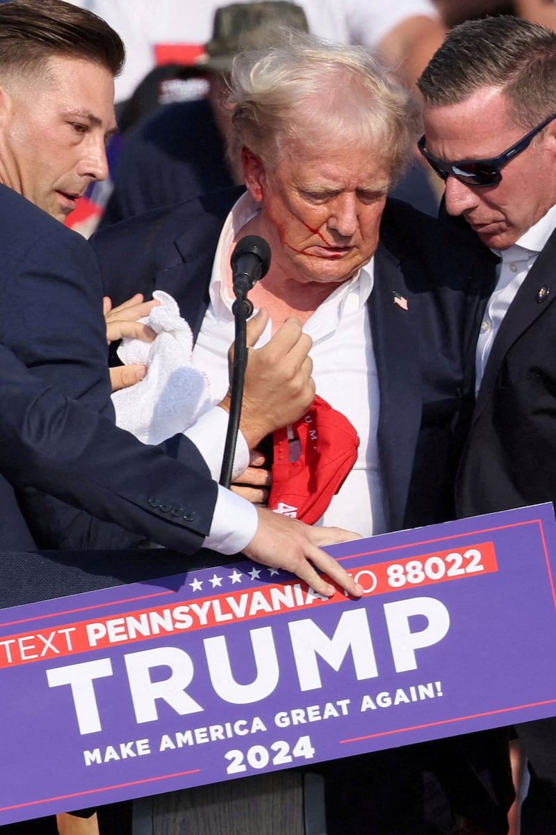 Bloodied Donald Trump with Secret Service agents tending to him at a rally.