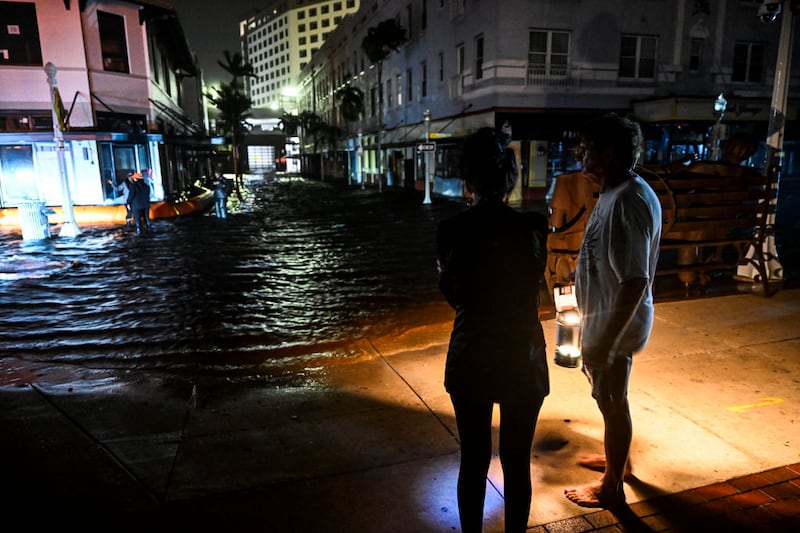 People watch water-flooded streets after Hurricane Milton made landfall in Fort Myers, Florida, on October 9, 2024. 