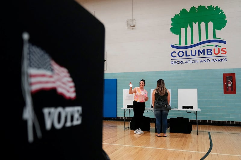 Volunteer Amelia Klein helps voters cast their ballots during a special election for Issue 1 in Columbus, Ohio.