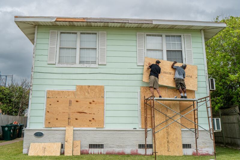 Dane Allen and Randy Davis board up apartments ahead of Tropical Storm Beryl's arrival. 