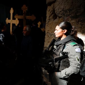 A member of the Israeli police force stands by as worshippers carry crosses during a Good Friday procession along the Via Dolorosa in Jerusalem's Old City April 22, 2022. 