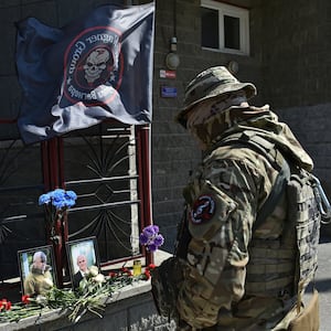 A Wagner fighter stands in front of a makeshift memorial with portraits of mercenary chief Yevgeny Prigozhin and Wagner group commander Dmitry Utkin outside the local Wagner office in Novosibirsk, Russia, Aug. 24, 2023. 