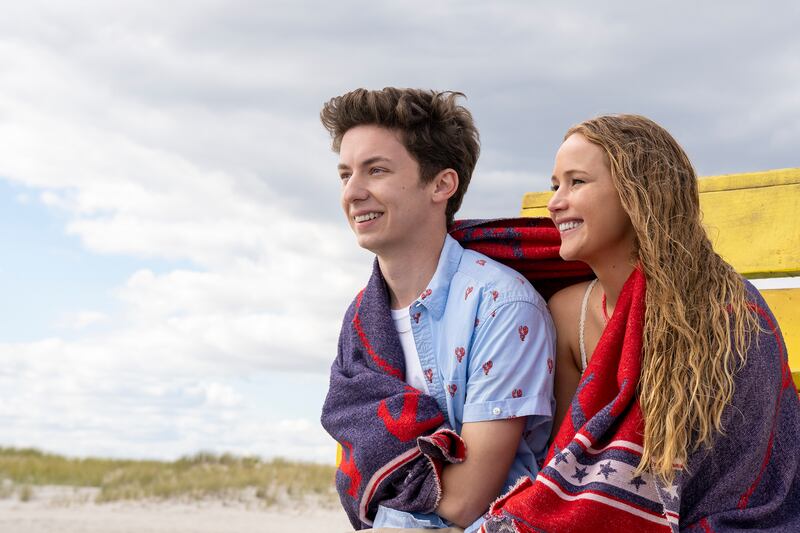 Jennifer Lawrence and Andrew Feldman sit on a beach during a scene from the movie No Hard Feelings.