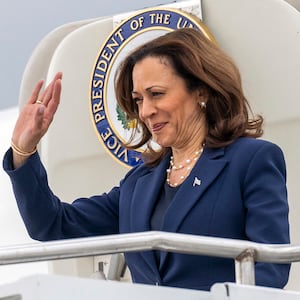 Kamala Harris waves as she steps off a plane.