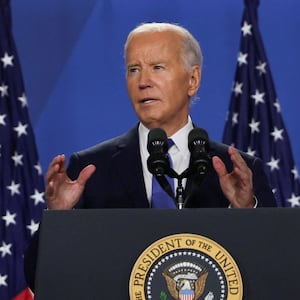 Joe Biden gesticulates behind a lectern with the presidential seal