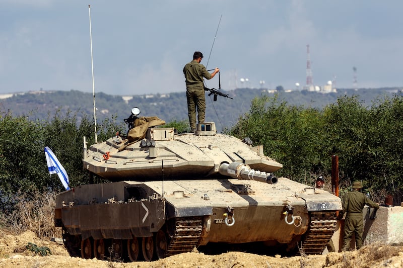 A photo including an Israeli soldier near Israel's border in Lebanon in Northern Israel