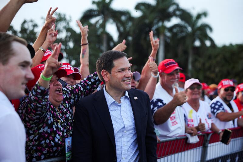 Marco Rubio smiles in front of supporters for Donald Trump.