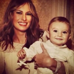 Melania Trump smiles as she holds an infant-aged Barron Trump, her now-18-year-old son.