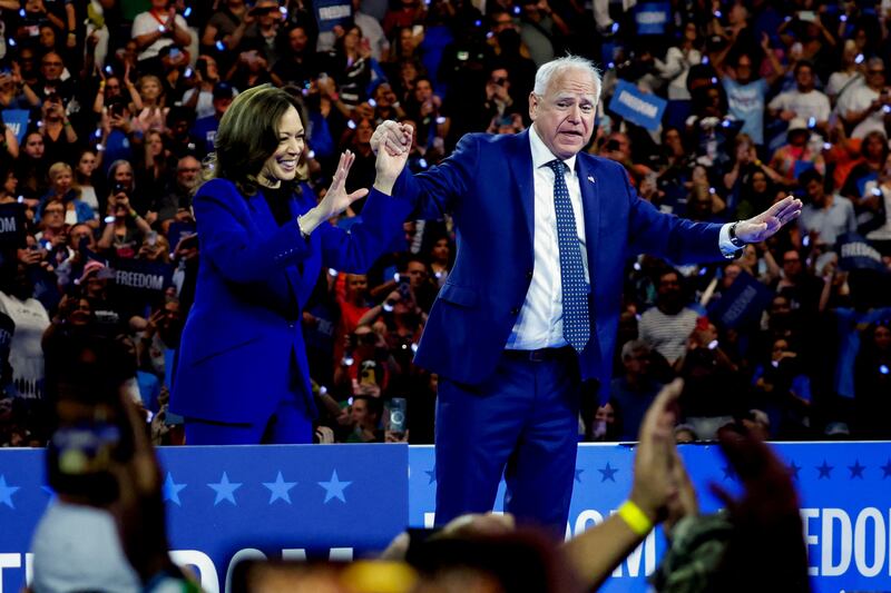 Kamala Harris and Tim Walz raise their hands together on stage 