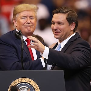 Donald Trump and Ron DeSantis stand in front of a podium.