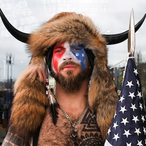 Jacob Chansley, also known as Jake Angeli, with his face painted in the colors of the U.S. flag, poses for a picture as supporters of U.S. President Donald Trump gather.